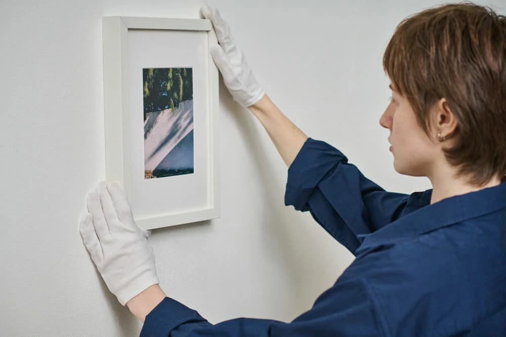 woman hanging framed photo on the wall